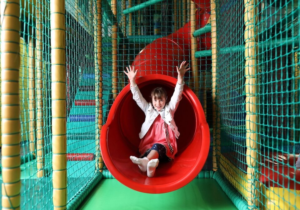 Mädchen rutscht im Funpark auf der Rutsche hinunter