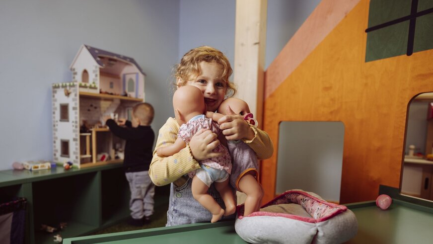 Mädchen spielt mit Puppenhaus