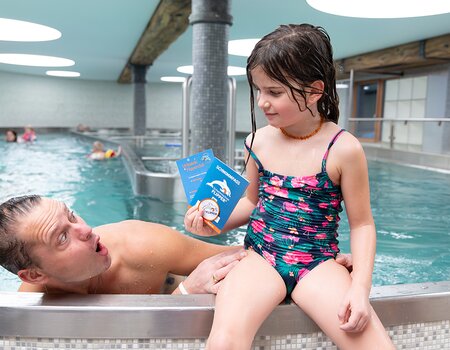 Mädchen hält Schwimmabzeichen in der Hand